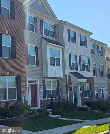 a front view of a residential apartment building with a yard and potted plants