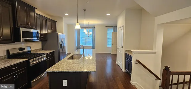 a large kitchen with stainless steel appliances granite countertop a stove refrigerator and a wooden floor