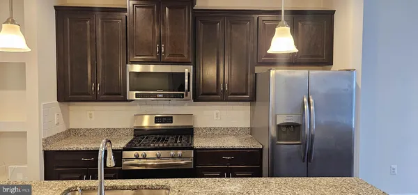 a kitchen with granite countertop a refrigerator and a stove top oven