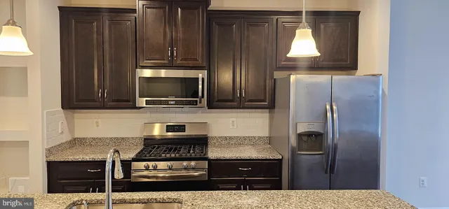 a kitchen with granite countertop a refrigerator and a stove top oven