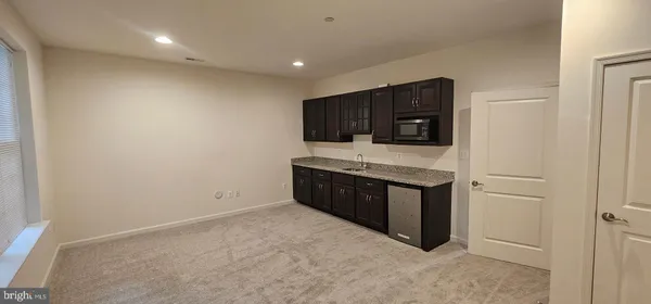 a large white kitchen with a sink and dishwasher a stove top oven with wooden floor