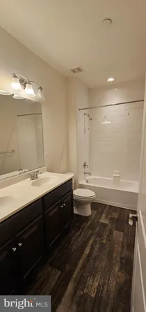 a bathroom with a double vanity sink and mirror with toilet