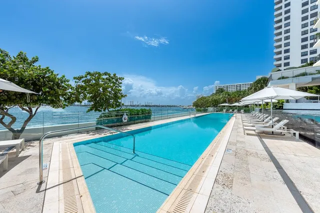 a view of swimming pool with lawn chairs under an umbrella