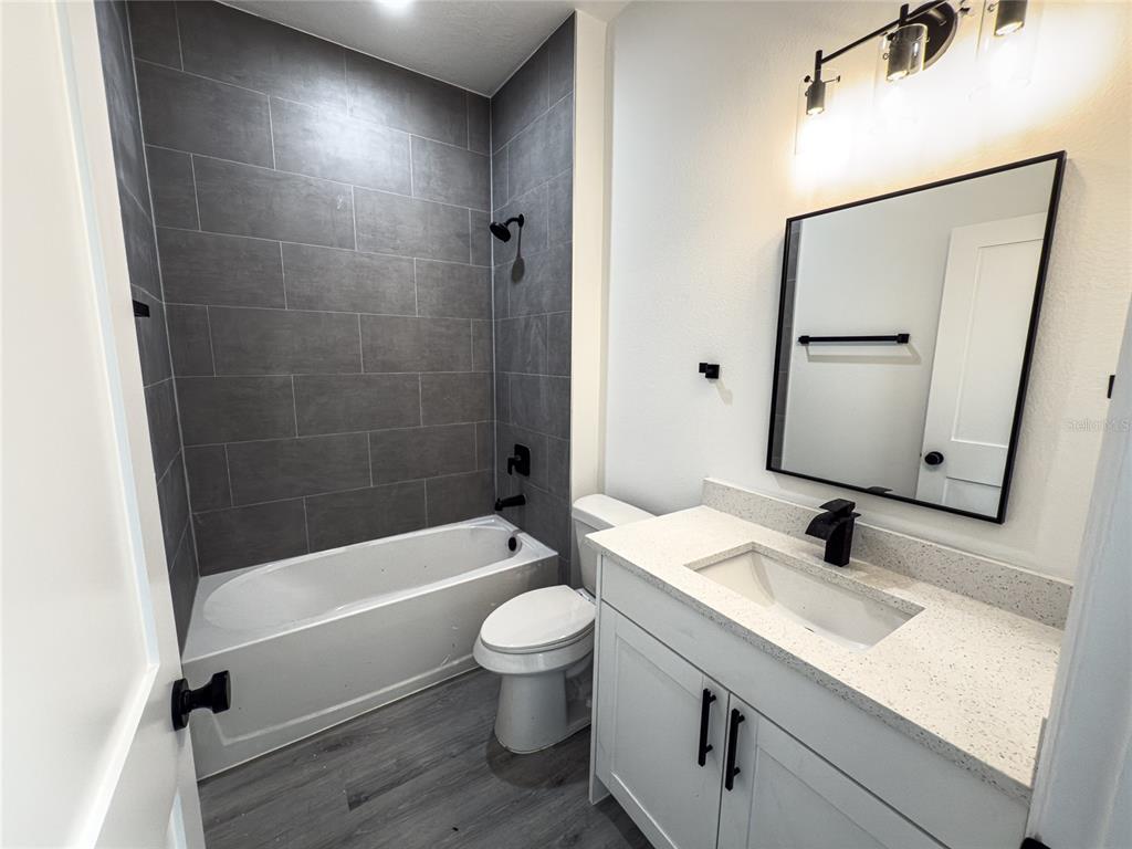 14481 Southwest 29th Terrace Ocala, FL 34473 - Photo 26 of 31 a bathroom with a granite countertop sink toilet a mirror a vanity and bathtub