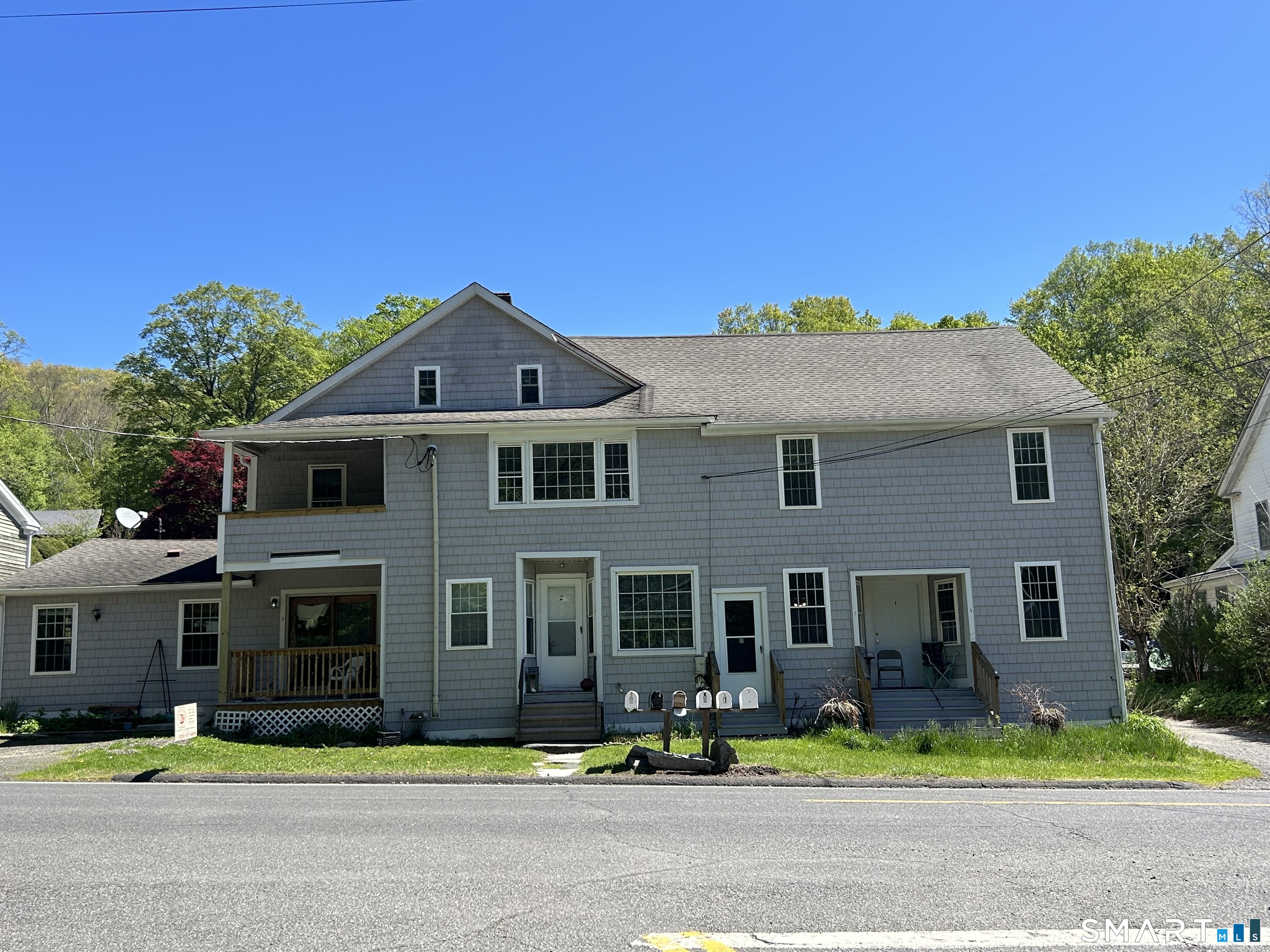 a front view of a house with yard and trees in the background