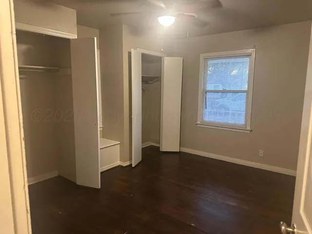 an empty room with wooden floor closet and windows