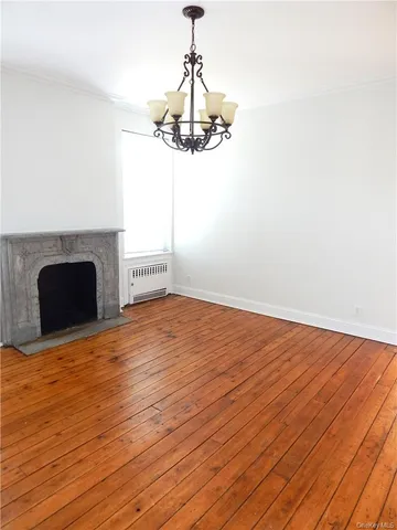 a view of empty room with wooden floor fireplace and chandelier