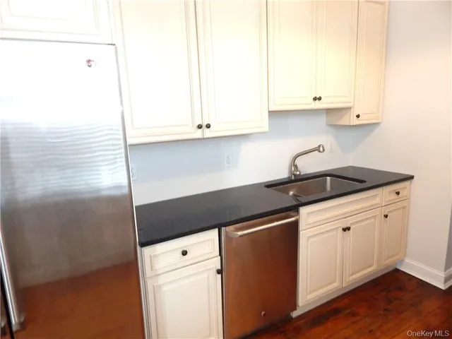 a kitchen with granite countertop white cabinets and a sink