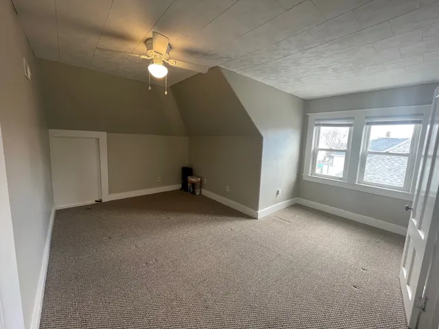 an empty room with a window and a ceiling fan