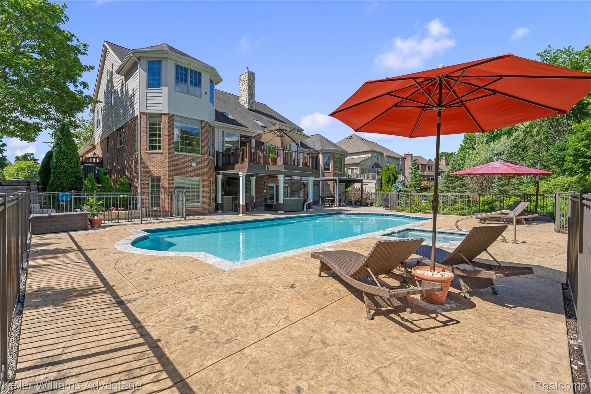 22878 Tree Top Court South Lyon, MI 48178 - Photo 50 of 75 Expansive backyard featuring a large swimming pool with an integrated spa, surrounded by stamped concrete decking