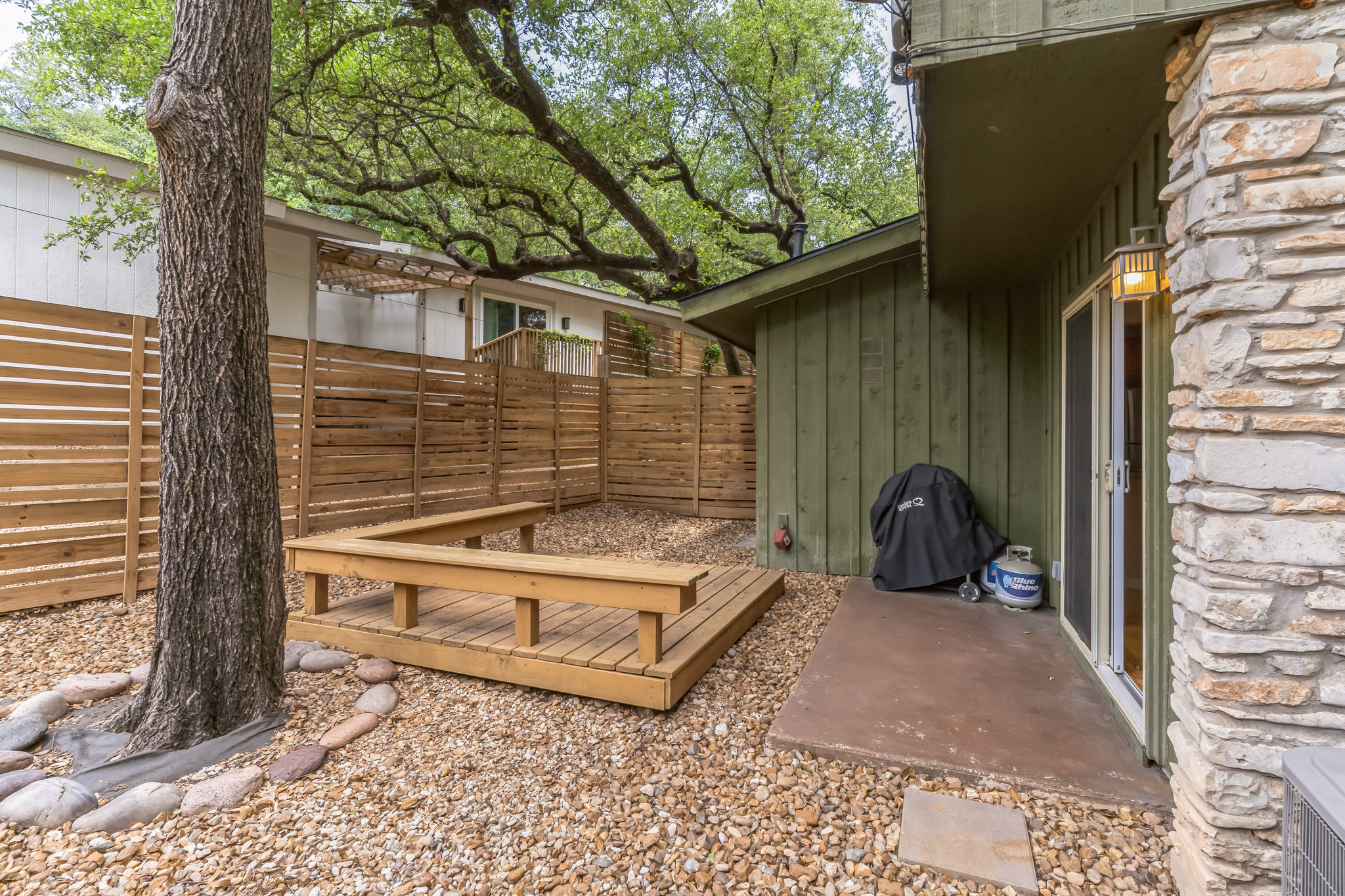 3214 Clawson Road, Unit A Austin, TX 78704 - Photo 22 of 26 A private, gravel-filled yard with a custom-built wooden deck bench, perfect for outdoor gatherings.