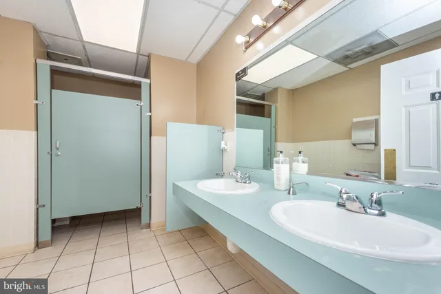 a spacious bathroom with a double vanity sink a mirror and a shower