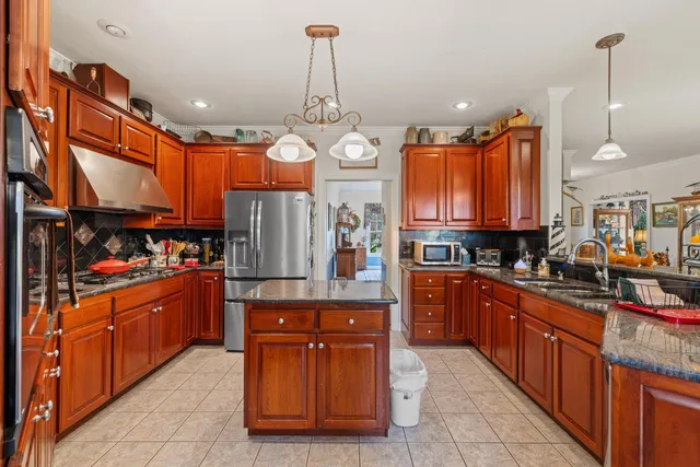 a kitchen with stainless steel appliances granite countertop a stove top oven a dining table and chairs with wooden floor