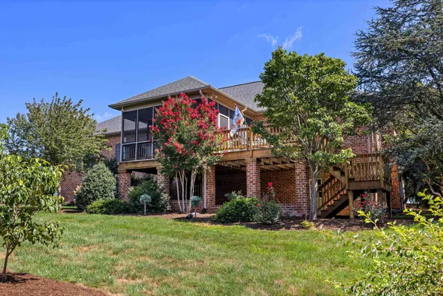 a brick house with a big yard and large trees