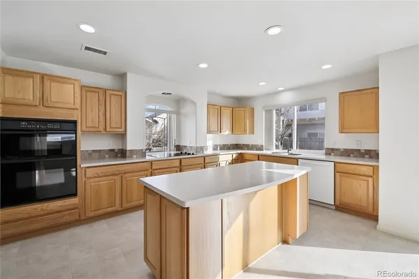 a large kitchen with stainless steel appliances granite countertop a sink and dishwasher a stove a refrigerator with wooden cabinets