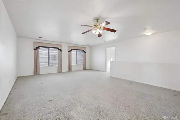 a view of an empty room with chandelier fan