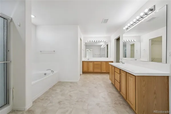 a bathroom with a tub a sink and a large mirror