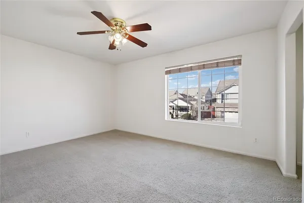 an empty room with window and ceiling fan