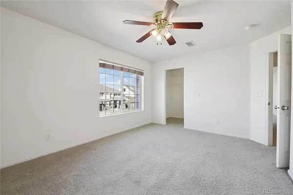 an empty room with windows and fan