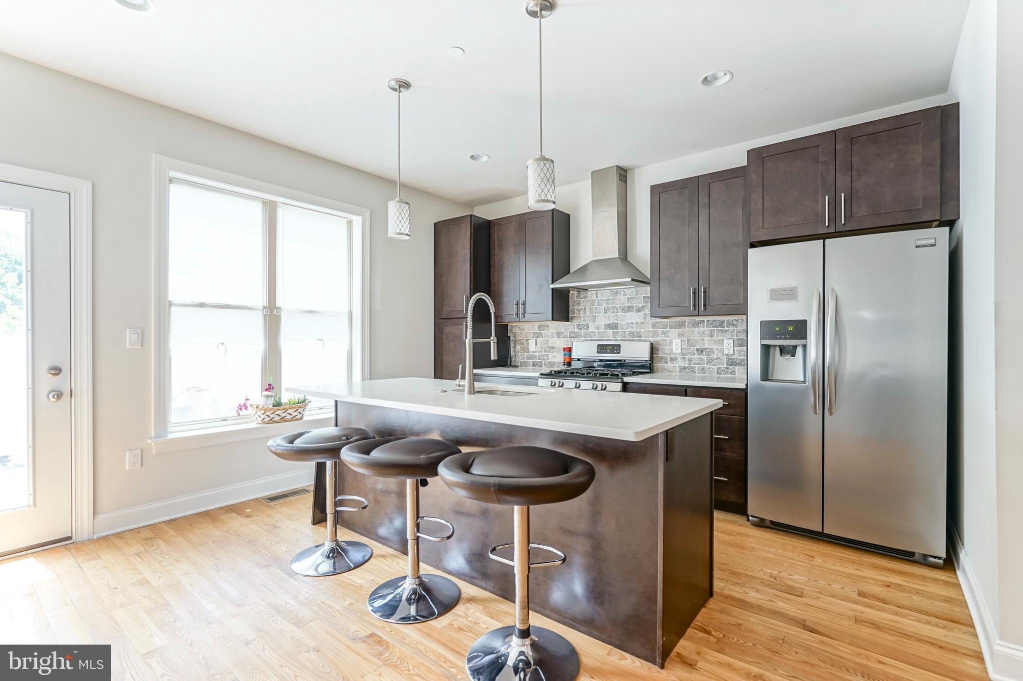 2332 Ellsworth Street Philadelphia, PA 19146 - Photo 6 of 29 a kitchen with stainless steel appliances granite countertop a sink a stove a refrigerator and island with wooden floor