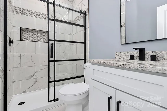 a bathroom with a granite countertop sink a toilet and shower