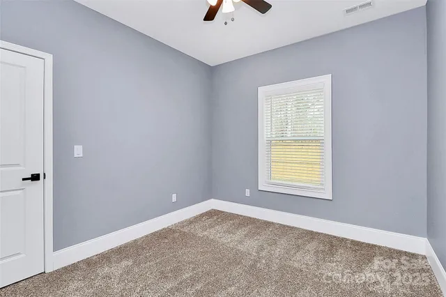 an empty room with a window and a ceiling fan