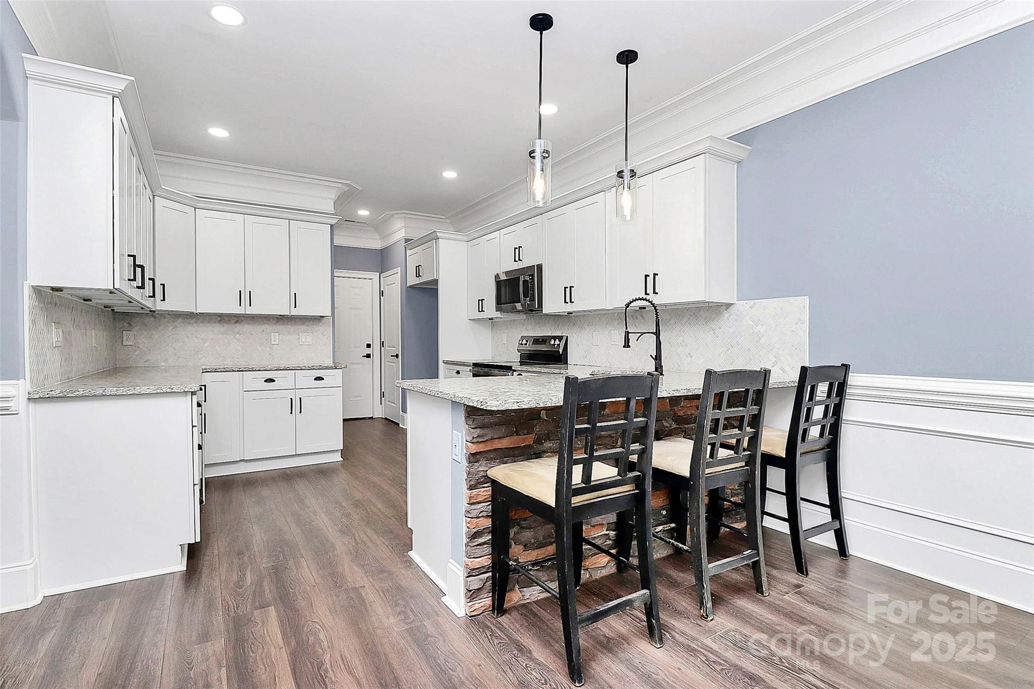 6519 Pargo Road Charlotte, NC 28216 - Photo 27 of 37 a kitchen with stainless steel appliances a dining table chairs stove and white cabinets