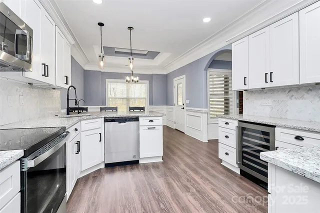 a kitchen with kitchen island granite countertop a sink cabinets and stainless steel appliances