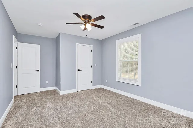 a view of a livingroom with a ceiling fan & windows