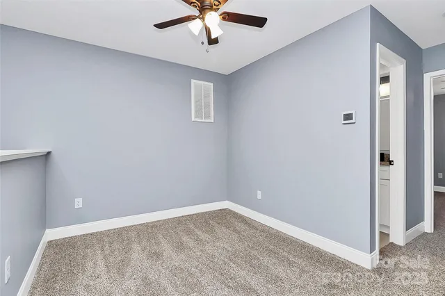 an empty room with a ceiling fan and carpet