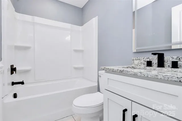 a bathroom with a granite countertop sink a toilet and bathtub