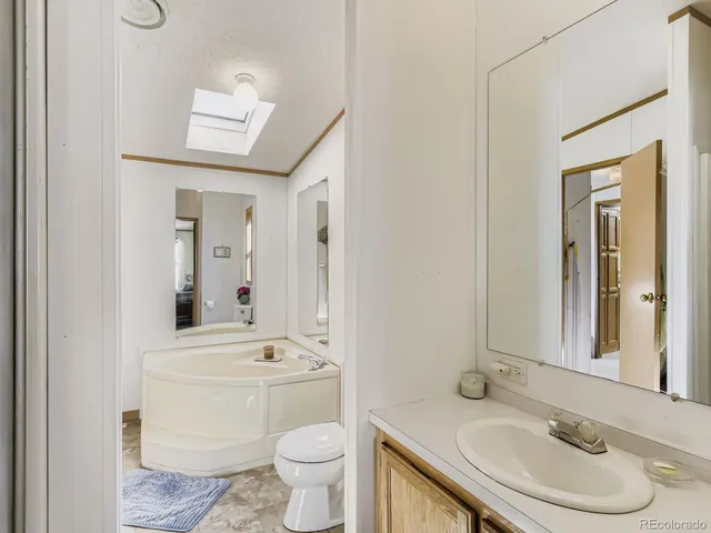 a bathroom with a granite countertop sink toilet a mirror and bathtub