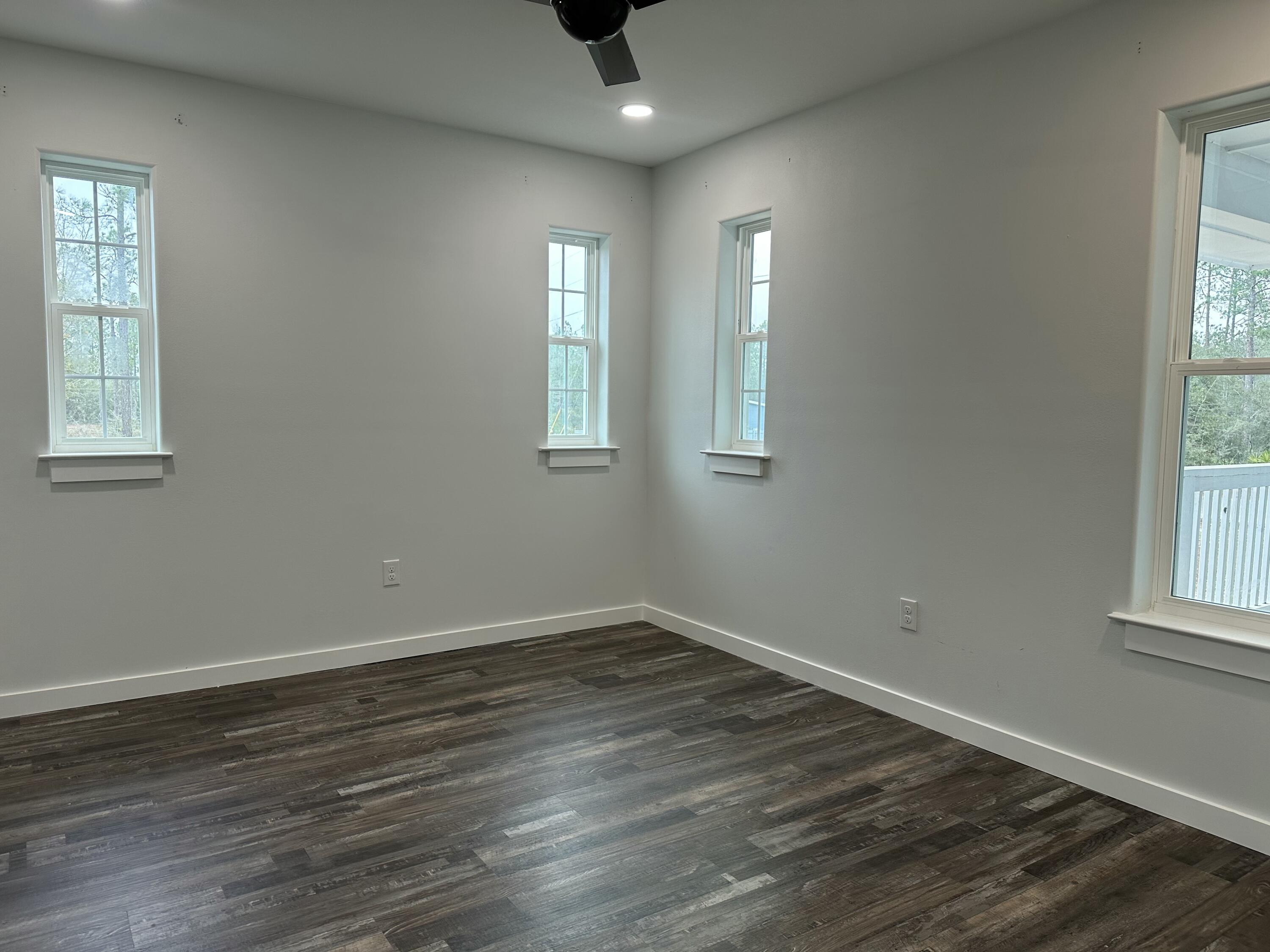 524 North Raphael Road DeFuniak Springs, FL 32433 - Photo 8 of 15 an empty room with wooden floor and windows