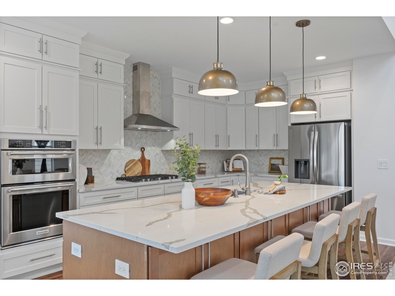 5070 Kidd Street Timnath, CO 80547 - Photo 16 of 42 a kitchen with kitchen island granite countertop a stove a sink a refrigerator and a cabinets