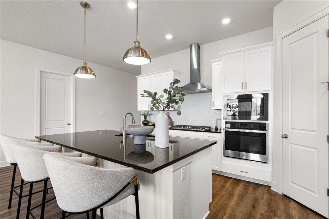 908 Knowles Drive Hutto, TX 78634 - Photo 6 of 37 a kitchen with kitchen island granite countertop a sink a counter space appliances and cabinets