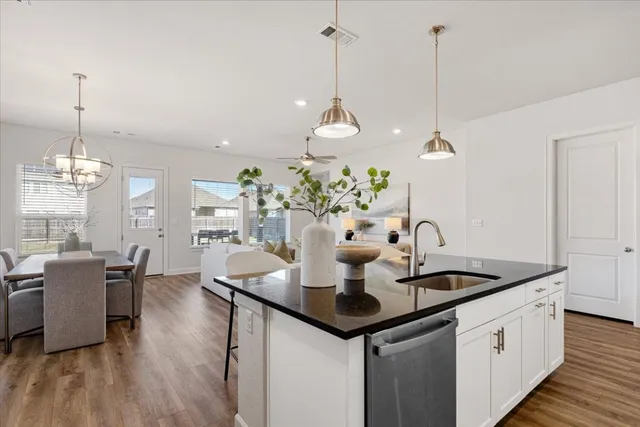 a kitchen island with granite countertop a sink cabinets and wooden floor