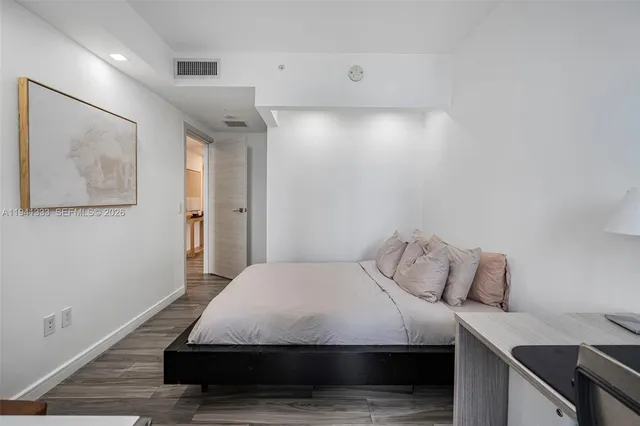 a view of a hallway with wooden floor and a bathroom