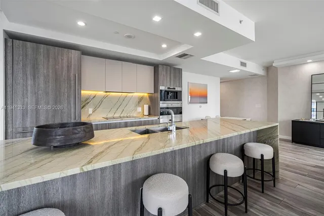 a large kitchen with stainless steel appliances a large counter top a stove and a sink