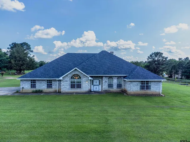 a view of a house with a yard and large trees