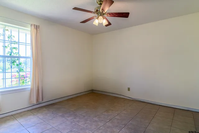an empty room with windows and fan