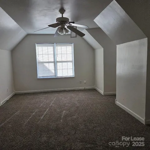 an empty room with a chandelier fan and windows