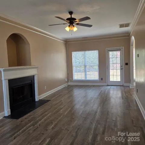 a view of an empty room with wooden floor and a fireplace