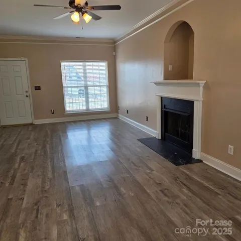 a view of an empty room with wooden floor fireplace and a window