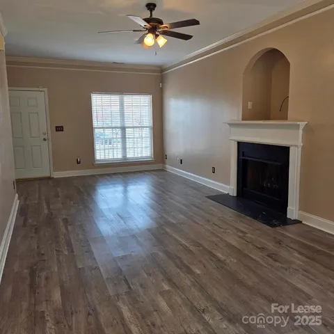 a view of an empty room with wooden floor fireplace and a window
