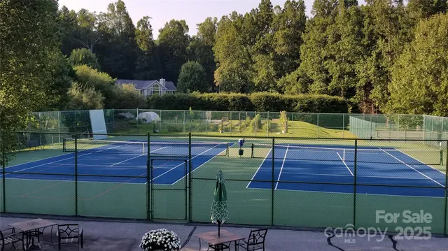 a view of a tennis ground with large trees