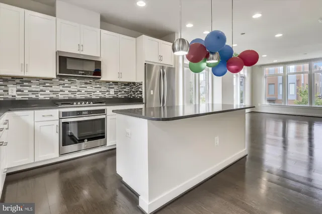 a kitchen with kitchen island wooden floor stainless steel appliances and a sink