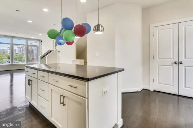 a kitchen with a sink a chandelier stainless steel appliances and cabinets