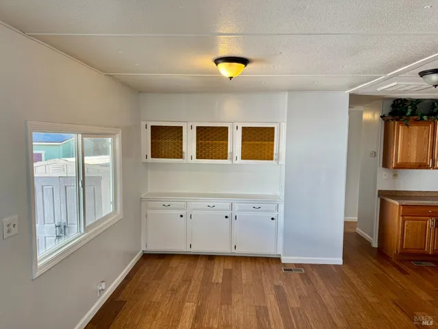 a view of an empty room with window and wooden floor