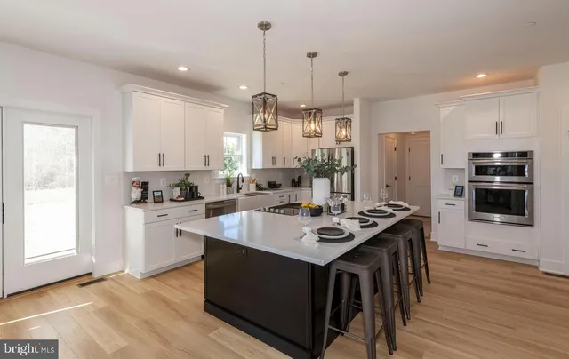 a kitchen with stainless steel appliances a sink a refrigerator and white cabinets