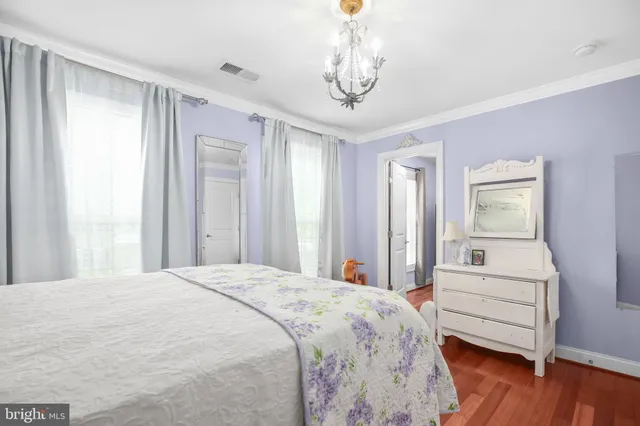 a bedroom with a bed and dresser with wooden floor